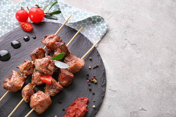 Barbecue skewers with juicy meat and sauce on slate plate