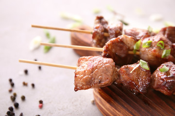Barbecue skewers with juicy meat on wooden board, closeup