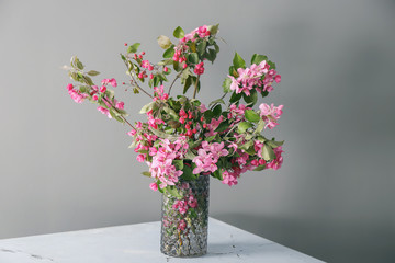 Vase with beautiful blossoming branches on grey background