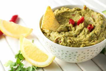 Bowl with delicious guacamole and lemon on wooden table