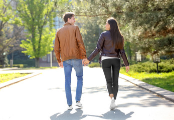 Happy young couple walking together in city park