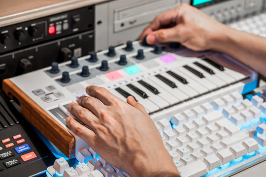 musician hands adjust midi keyboard knob for recording in digital sound editing studio