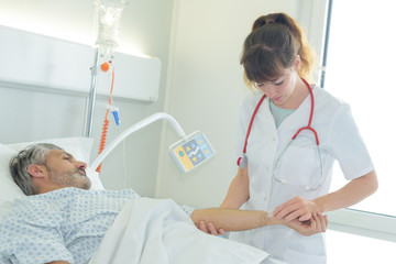 doctor examining patients pulse in hospital room