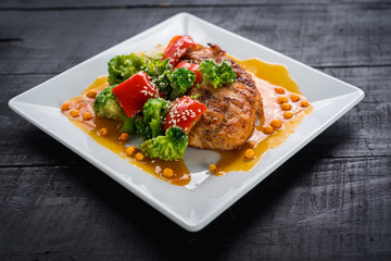 Tasty fried chicken meat with vegetables and lentils sauce on wooden background