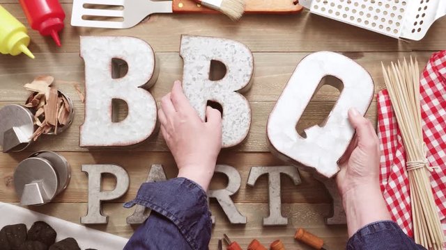 Metal BBQ Party sign with grilling tools on wood background