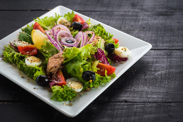 Salad with pieces of meat and vegetables on wooden background