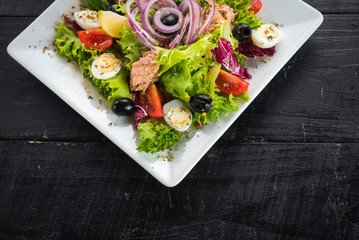 Salad with pieces of meat and vegetables on wooden background