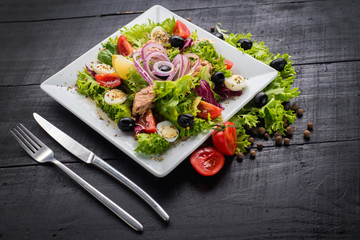 Salad with pieces of meat and vegetables on wooden background
