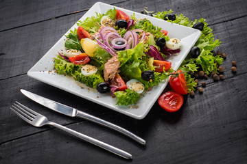 Salad with pieces of meat and vegetables on wooden background