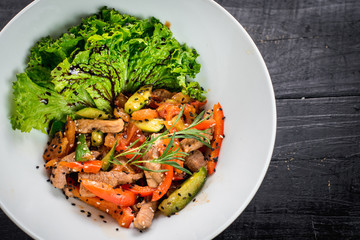Salad from meat with red pepper and soy sauce on wooden background