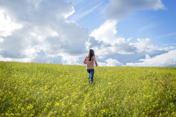 happy girl in a yellow flower field with a dandelion in her hand