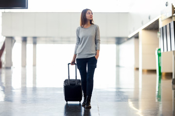 Young woman with suitcase in airport terminal