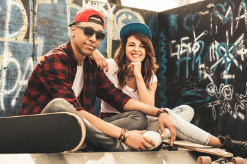 Young teen couple sitting by the wall and hangout at the street .Embrace each other and laughing . © BalanceFormCreative