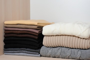 Different knitted sweaters  in a wardrobe, close up. Concept warm clothing.