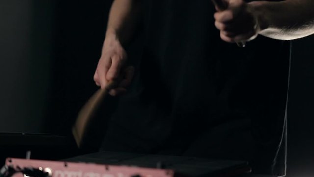 Close up shot of man's hands drum sticks on sampler and electronic pads