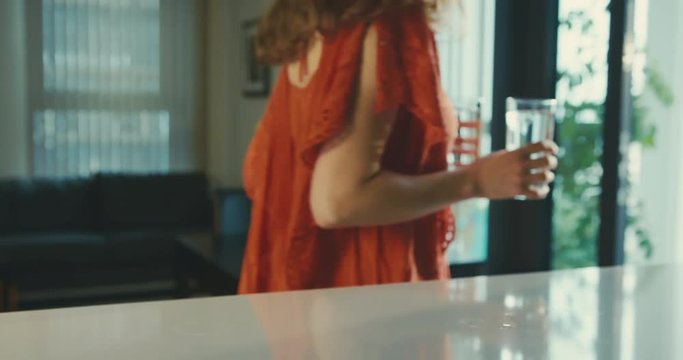 Woman in red dress picking up glasses of water