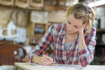 emale apprentice taking notes in workshop
