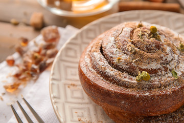 Sweet cinnamon bun on plate, closeup