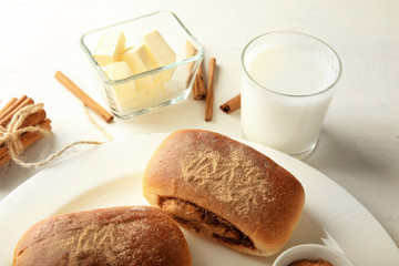 Plate with sweet cinnamon buns on table