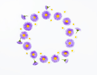 Floral wreath made of violet flowers and chamomile on white background. Flat lay. Top view with copy space.