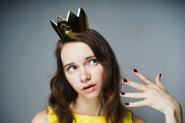 funny young woman in yellow dress posing, head on golden crown
