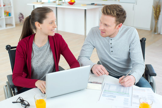 Couple In Wheelchairs Doing Their Accounts