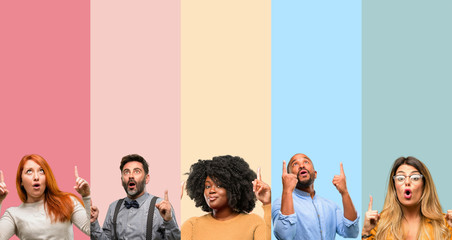 Cool group of people, woman and man happy and surprised cheering expressing wow gesture pointing up - obrazy, fototapety, plakaty