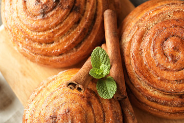 Sweet cinnamon buns on wooden board, closeup