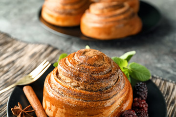 Plate with sweet cinnamon bun on table