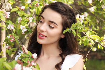 Fototapeta premium Beautiful young woman near blossoming tree on sunny spring day