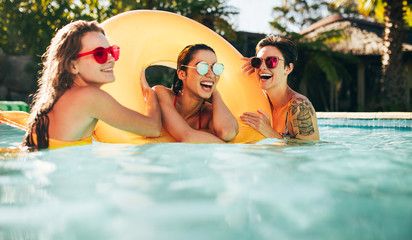 Female friends enjoying summer at pool - obrazy, fototapety, plakaty