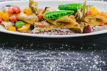 Dessert strudel with caramelized fruits on wooden background.