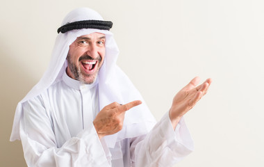 Senior arabic man very happy pointing with hand and finger