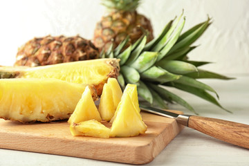 Board with delicious cut pineapple on table