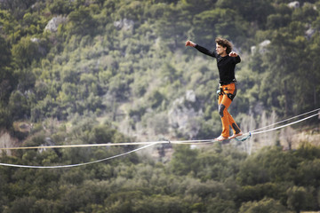 Highliner on a rope. Highline on a background of mountains. Extreme sport on the nature. Balancing...