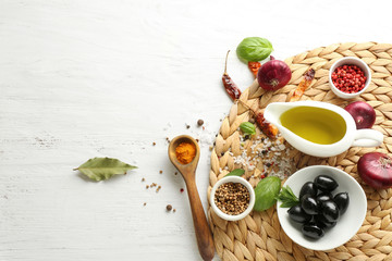 Gravy boat with olive oil and spices on wicker mat