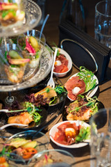 Tasty little snacks with meat and vegetables on served table at the restaurant