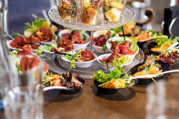Tasty little snacks with meat and vegetables on served table at the restaurant