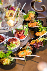 Tasty little snacks with meat and vegetables on served table at the restaurant