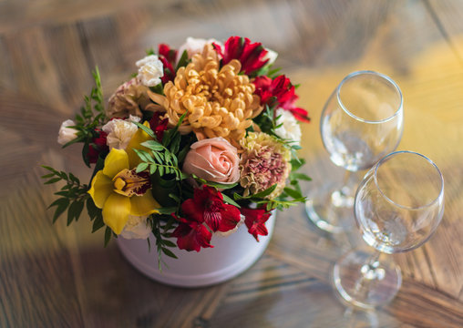 .Beautiful fresh flowers in a round box and empty glasses are on the table. A date at the restaurant.