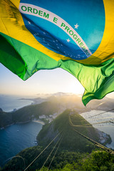 Brazilian flag shines above the golden sunset city skyline at Sugarloaf  Mountain in Rio de Janeiro Brazil. 