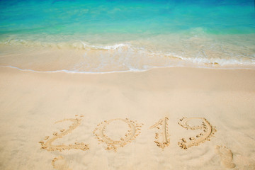 Fototapeta na wymiar Inscription on the sand, celebrate the new year in the tropics. New year holidays