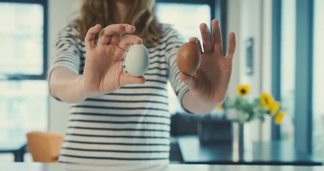 Young woman holding brown and blue egg