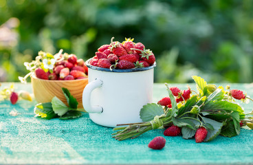 Fragrant wild strawberry in a mug on a old table. Outdoor.