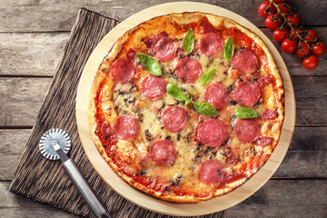 Wooden board with tasty pepperoni pizza on table