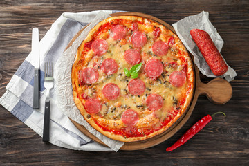 Wooden board with tasty pepperoni pizza on table