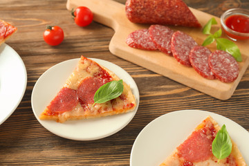 Plates with pieces of pepperoni pizza on table