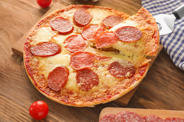 Taking piece of tasty pepperoni pizza with spatula