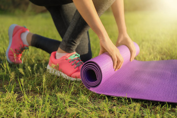 Sporty young woman with yoga mat in park