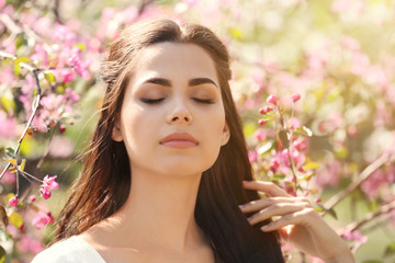 Naklejka premium Beautiful young woman near blooming tree in park on spring day